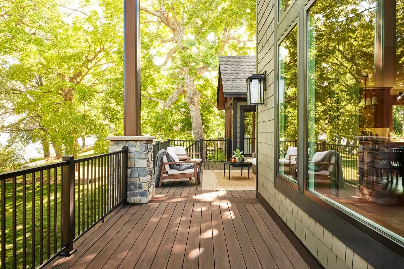 Outdoor living inspiration: a covered wood-toned deck with dark railings and seating overlooking trees