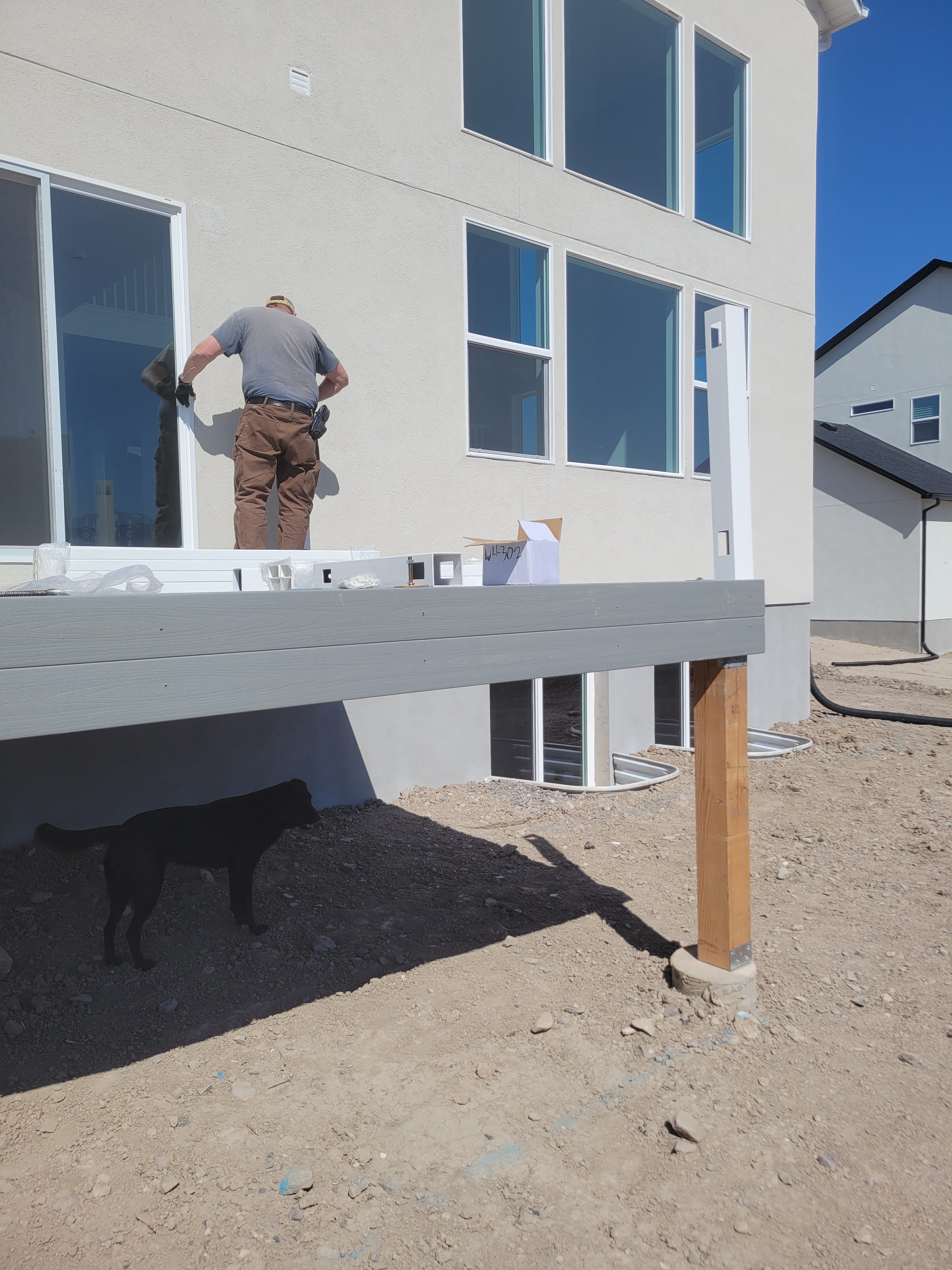 A worker installing a raised deck outside a home