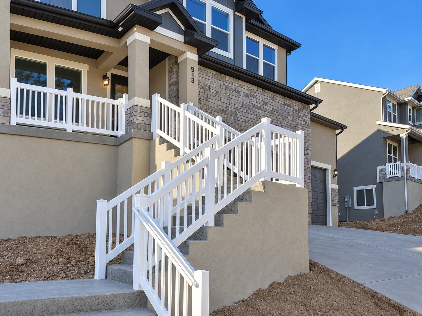 White railings following the front porch and concrete entry stairs of a home